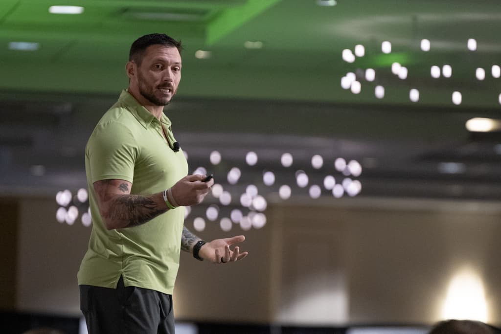 Nick Habich speaking on stage to a room of gym owners